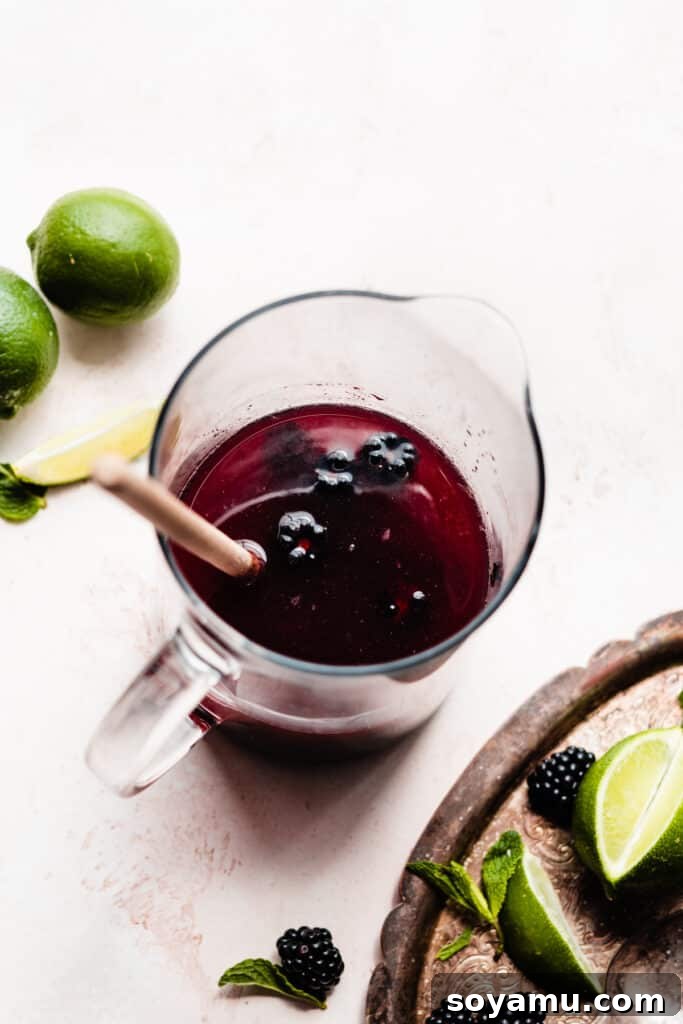 Blackberry Lime Fiesta Sangria 5 A pitcher showing muddled blackberries with the addition of limeade and brandy, ready for the next mixing step.