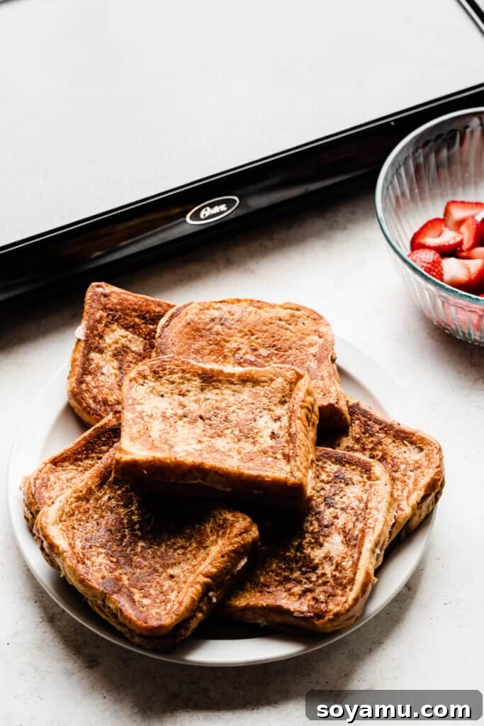 Decadent Stuffed French Toast 7 Perfectly cooked golden-brown french toast slices stacked on a plate.