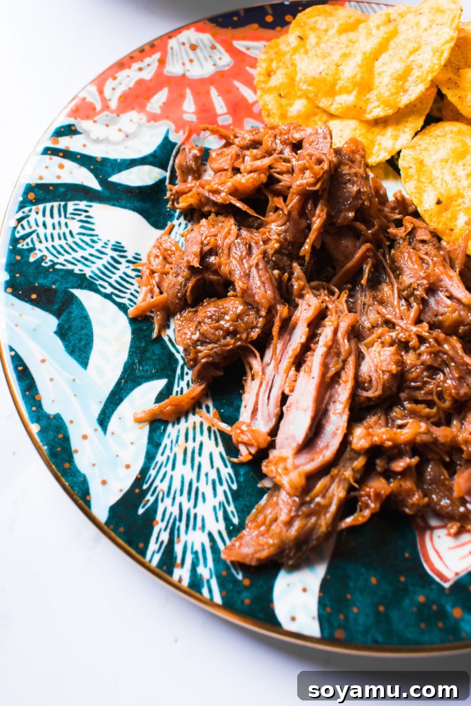 Perfectly Tender Instant Pot Pulled Pork 8 A beautifully presented plate of pulled pork tacos, garnished with fresh cilantro and lime, ready to eat.