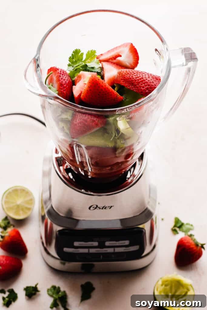 Blended Strawberry Fiesta 6 Large chunks of fresh strawberries placed on top of the other ingredients in the blender pitcher, ready for blending.