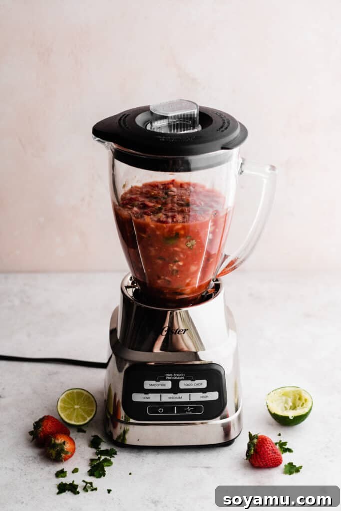 Blended Strawberry Fiesta 7 The Oster One Touch Blender with the freshly blended, chunky strawberry salsa inside, showing the ideal consistency.