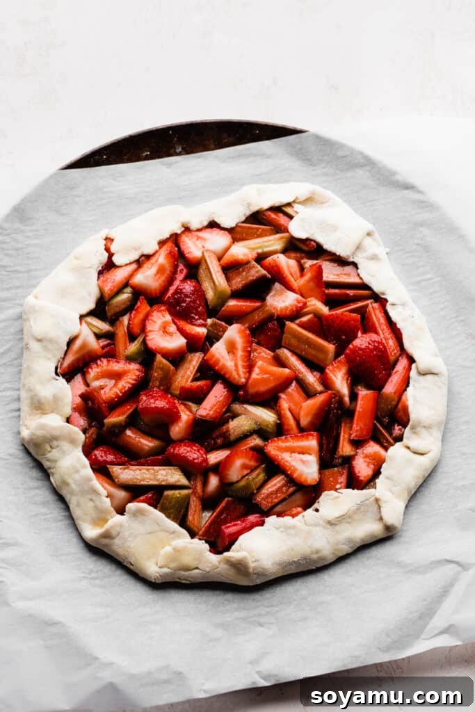 The vibrant strawberry and rhubarb filling nestled within the unbaked pie dough, with the edges folded gracefully to create a rustic border.