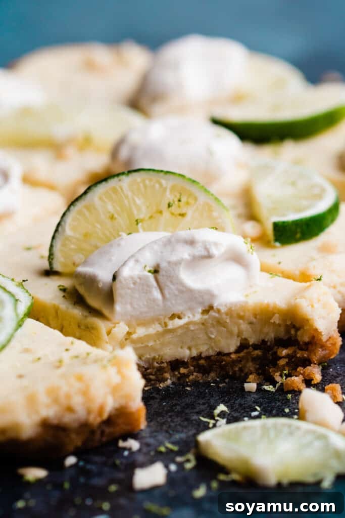 Tropical Key Lime Macadamia Bars 8 A close-up of a key lime pie bar with a bite taken from the creamy filling and crisp, buttery crust.