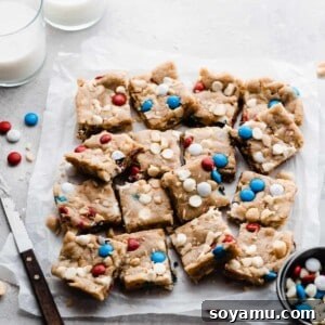 Vibrant M&M Fireworks Cookie Bars 7 Close-up of a delicious Fireworks Cookie Bar, showcasing its M&Ms, white chocolate chips, and macadamia nuts.