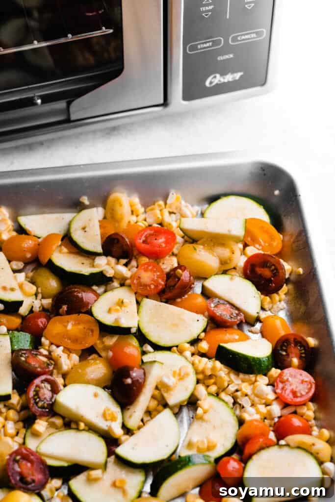 Vibrant Roasted Vegetables for Meal Prep 4 A pan of the raw, freshly sliced tomatoes, corn, and zucchini, ready for seasoning.