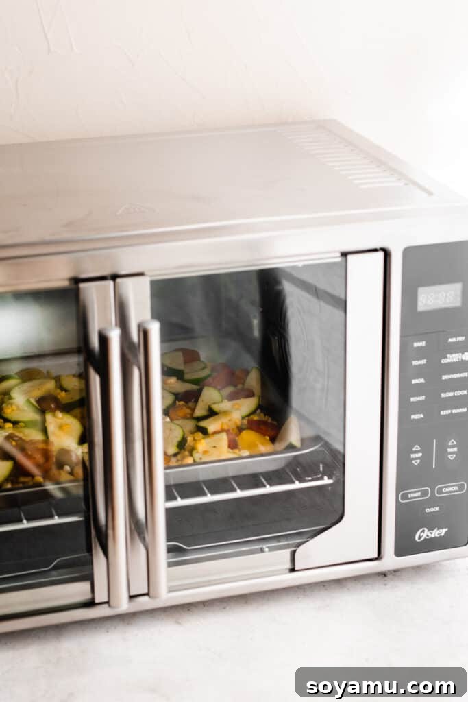 Vibrant Roasted Vegetables for Meal Prep 6 The pan of veggies roasting inside the air fryer with the doors closed, showing the internal light.