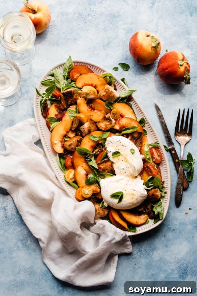 Peach Burrata and Basil Salad 2 A stunning platter of peach panzanella salad artfully arranged on a rustic blue surface, surrounded by elegant wine glasses and fresh, whole peaches, ready to be enjoyed.
