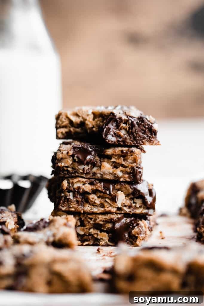 Chewy Brown Butter Chocolate Chunk Oatmeal Bars 10 A stack of the finished oatmeal chocolate chunk cookie bars, with a bite playfully taken out of the top piece, revealing the soft, chewy interior and melty chocolate.