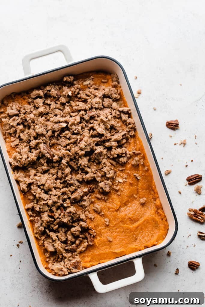 Candied Sweet Potato Casserole with Pecan Streusel 7 A pan of sweet potato filling with brown sugar pecan streusel crumbled over the top, ready for baking.