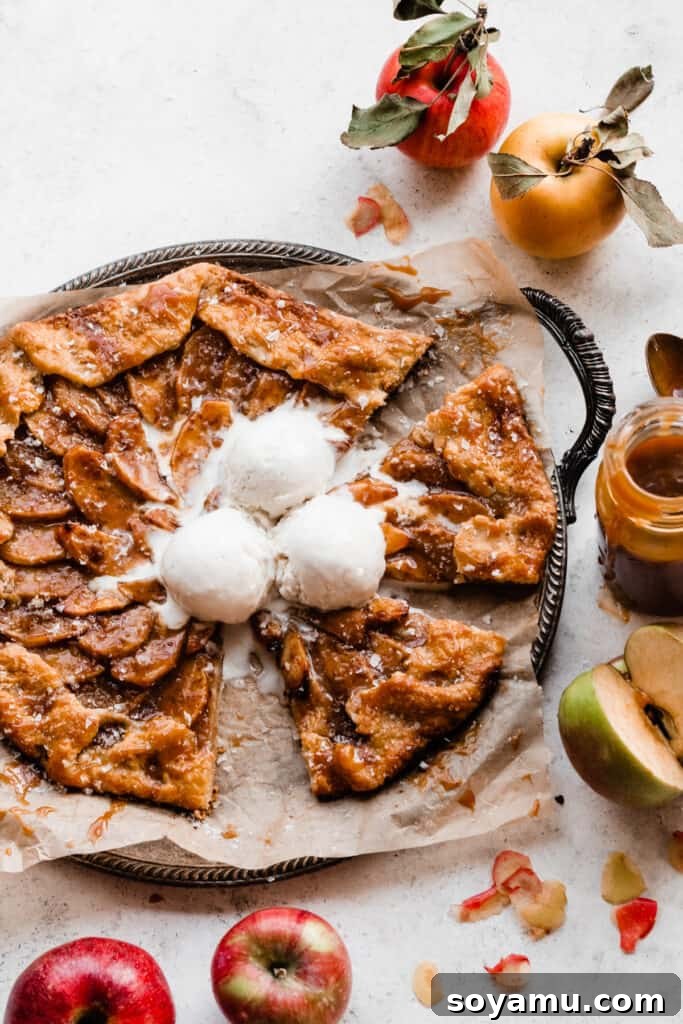 Salted Caramel Apple Galette Recipe 8 A freshly baked Salted Caramel Apple Galette, sliced and ready to serve, with two slices already removed and the remaining ones glistening with caramel and topped with melting vanilla ice cream.