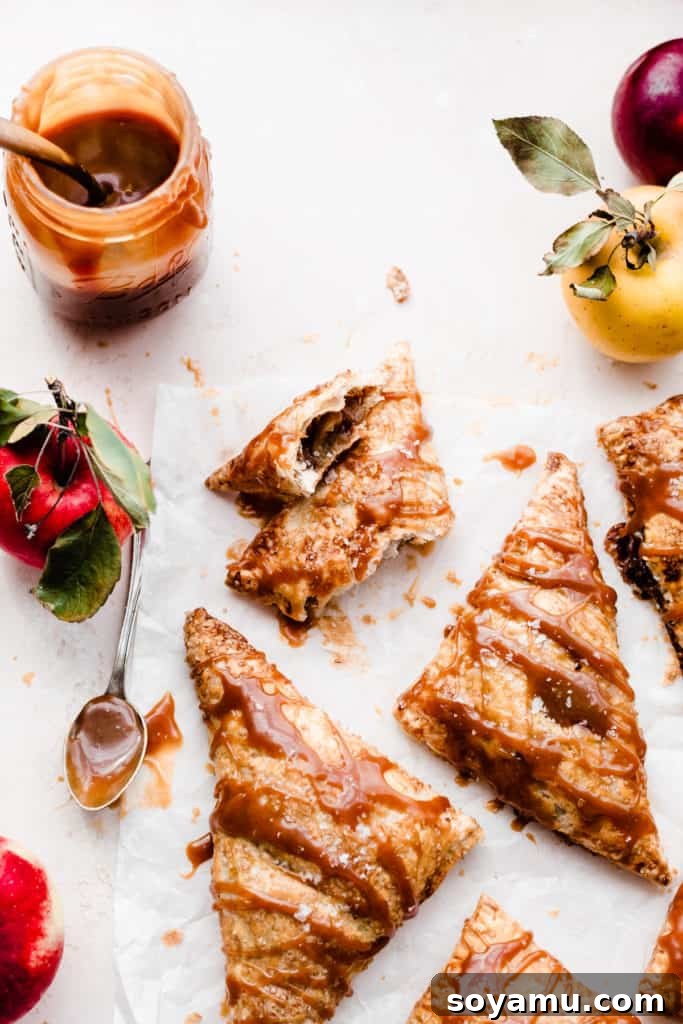 Autumns Best Apple Recipes Fresh from the Orchard 13 A close-up of several golden-brown Caramel Apple Turnovers, generously drizzled with rich caramel sauce.