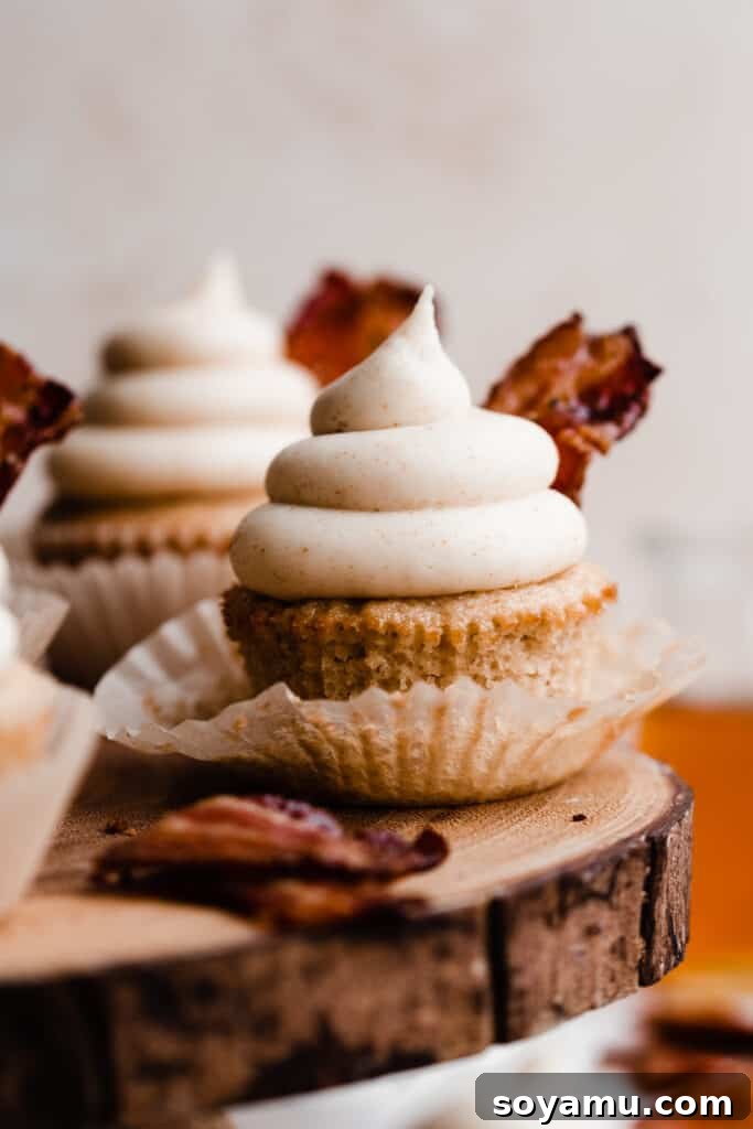 Brown Butter Maple Bacon Perfection 2 A close-up of a maple bacon cupcake topped with a swirl of frosting and candied bacon.