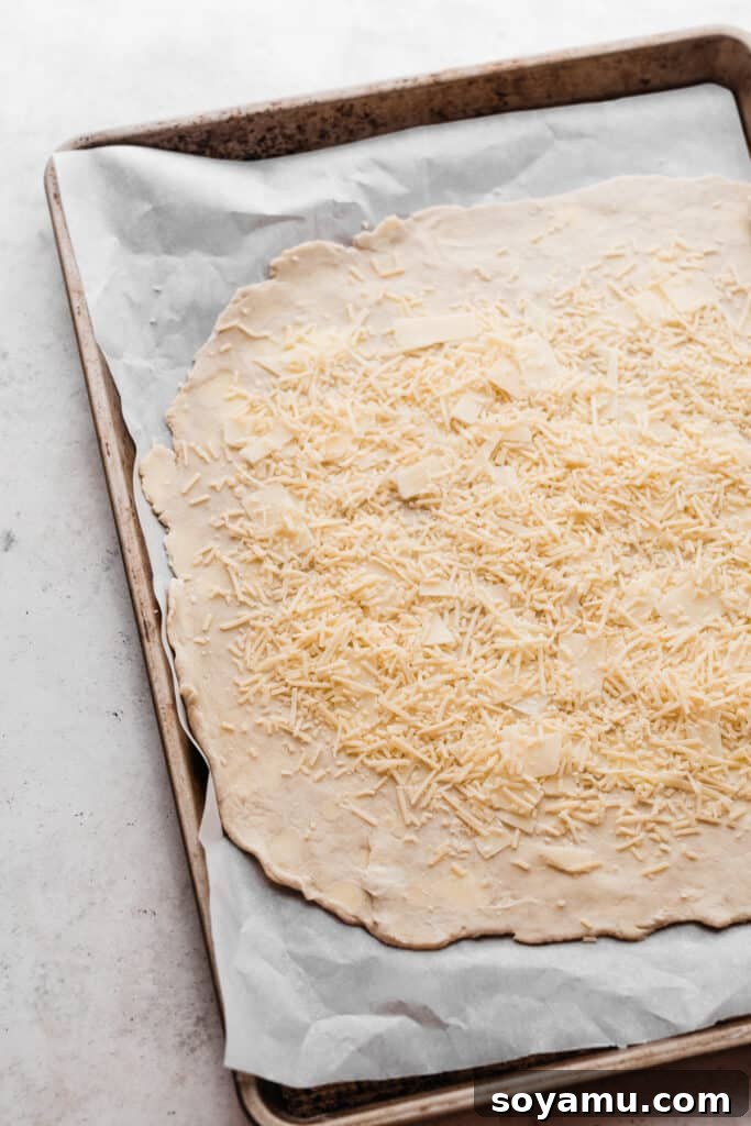Asiago Parmesan Butternut Squash Galette 5 Rolled out pie dough on a baking sheet, topped with a generous layer of grated Asiago and Parmesan cheese, leaving a border.