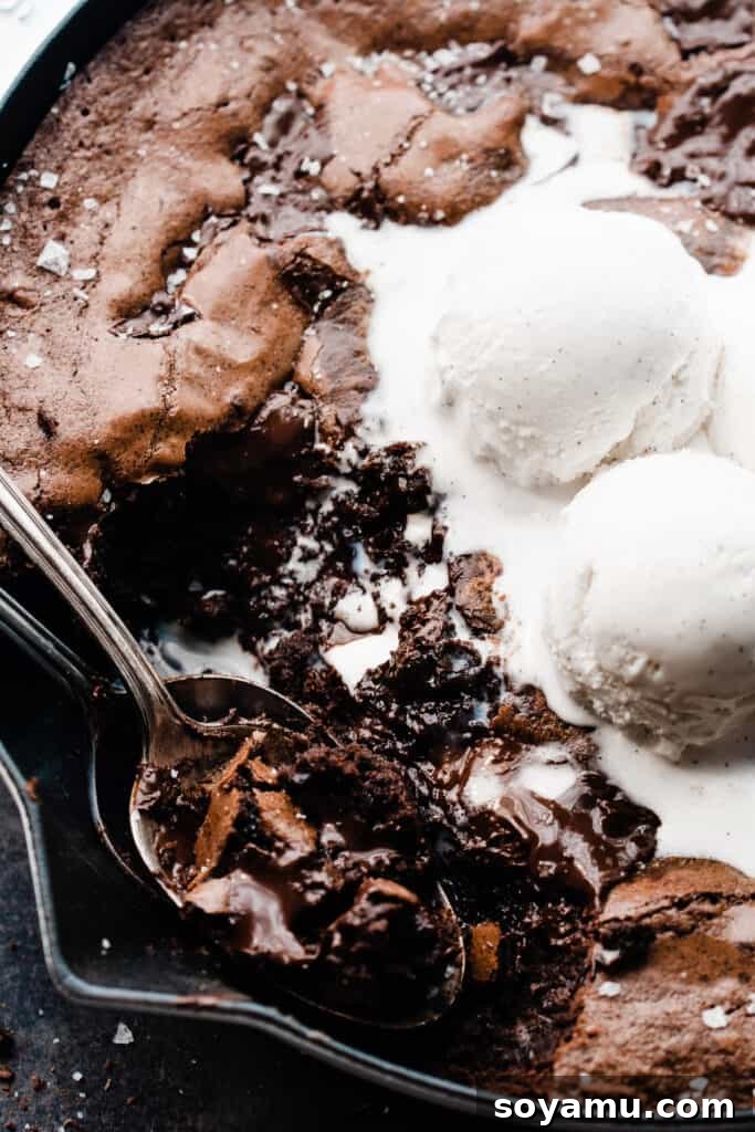 Ultimate Fudgy Triple Chocolate Skillet Brownie 3 A close-up shot of two spoons expertly scooping into the warm, gooey center of a skillet brownie, revealing its rich, melted chocolate pools.