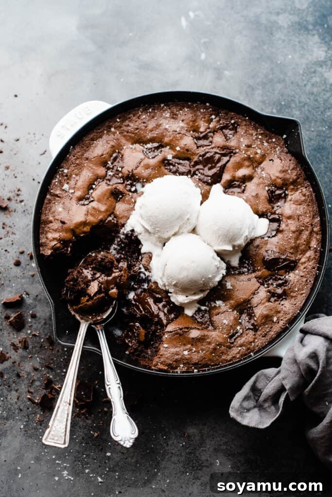 Ultimate Fudgy Triple Chocolate Skillet Brownie 8 A gooey skillet brownie, topped with a scoop of vanilla ice cream, showcasing its rich texture and perfect for sharing or enjoying solo.