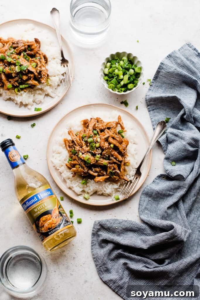Sticky Sweet Slow Cooker Honey Garlic Chicken 3 Two plates of delicious honey garlic chicken served over rice, with a bottle of white cooking wine and fresh green onions nearby, highlighting the key ingredients.