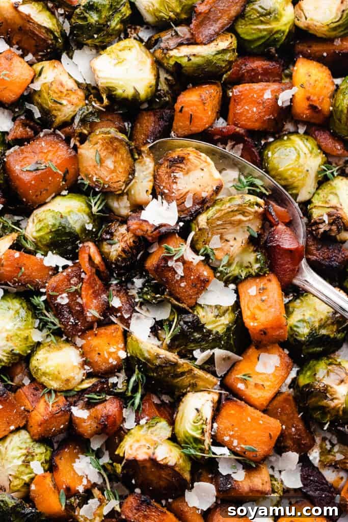 Sweet Maple Roasted Brussels Sprouts and Butternut Squash with Crispy Bacon 2 A serving spoon scoops into a vibrant, roasted medley of Brussels sprouts, butternut squash, and crispy bacon, garnished with fresh herbs and a sprinkle of Parmesan.