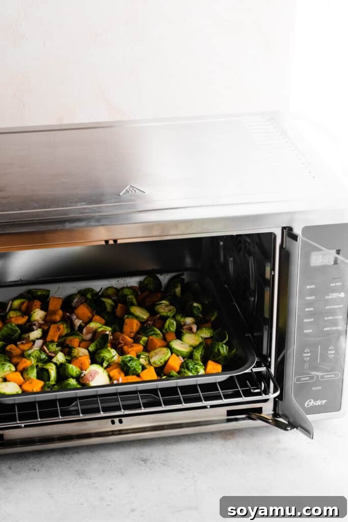 Sweet Maple Roasted Brussels Sprouts and Butternut Squash with Crispy Bacon 4 A baking sheet filled with seasoned Brussels sprouts, butternut squash, and bacon being carefully placed into the preheated Oster French Door Air Fry Oven.