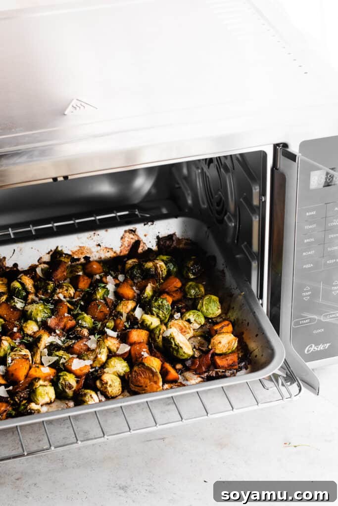 Sweet Maple Roasted Brussels Sprouts and Butternut Squash with Crispy Bacon 5 A baking sheet, laden with beautifully roasted Brussels sprouts, caramelized butternut squash, and crispy bacon, being carefully removed from the Oster French Door Air Fry Oven.