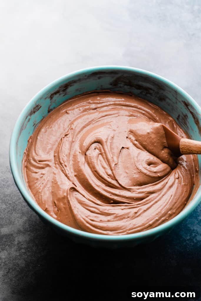 Baileys Infused Chocolate Ganache Cheesecake 5 Lustrous chocolate cheesecake batter, rich and smooth, filling a large mixing bowl.