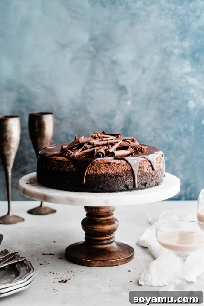Baileys Infused Chocolate Ganache Cheesecake 8 Bailey's Chocolate Cheesecake on a cake stand, elegantly topped with chocolate ganache and decorative chocolate curls.