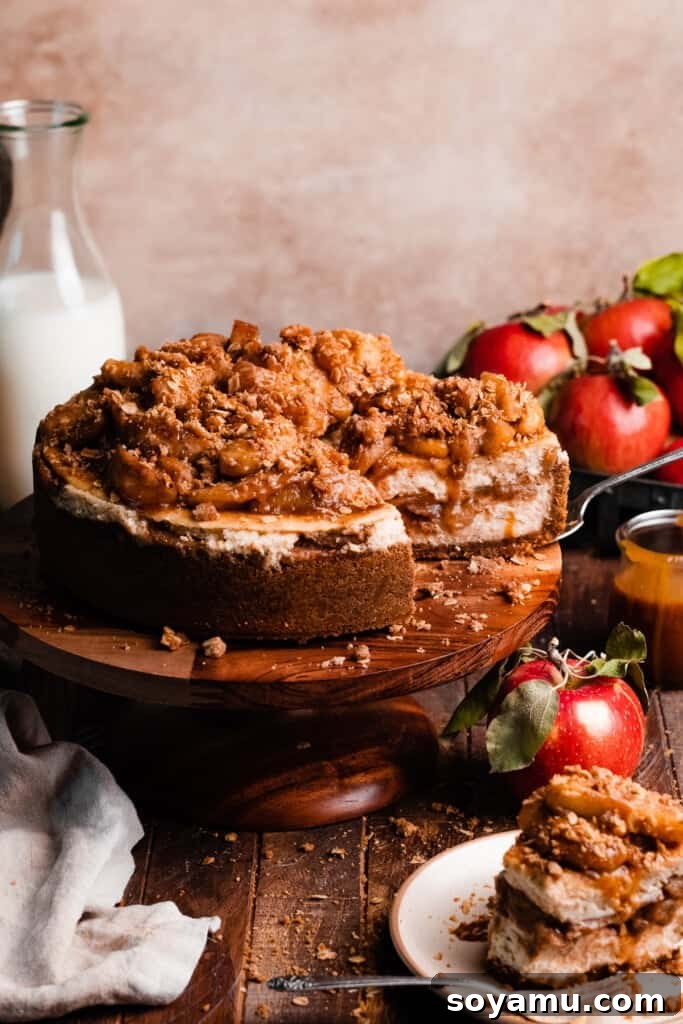 Decadent Salted Caramel Apple Pie Cheesecake 14 The fully assembled and sliced apple crumble cheesecake on a cake stand, adorned with rich apple filling, oat crumble, and a luscious caramel drizzle.