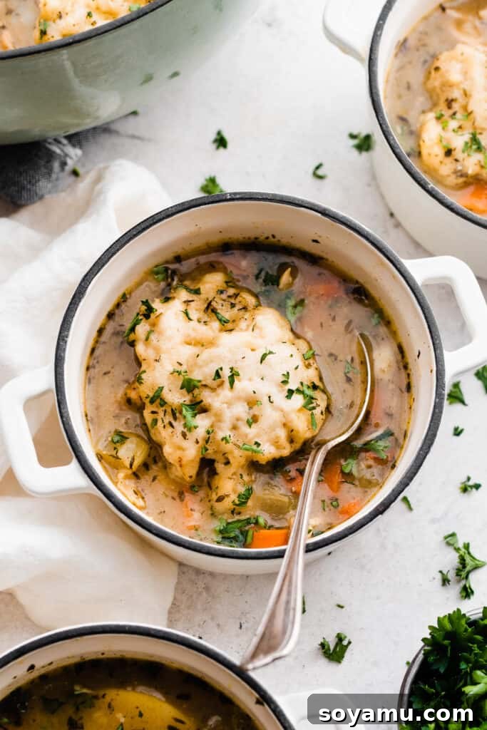 Soul-Soothing Chicken Dumpling Broth 11 Multiple bowls of chicken dumpling soup, garnished with fresh herbs, arranged on a rustic table setting.