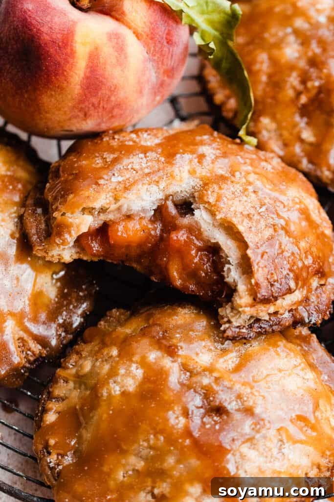 Salted Caramel Peach Mini Pies 2 A close up on a peach hand pie with a bite taken, revealing the juicy peach filling and flaky crust.