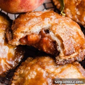 A close-up of a peach hand pie with a bite taken, revealing the juicy peach filling and flaky crust.