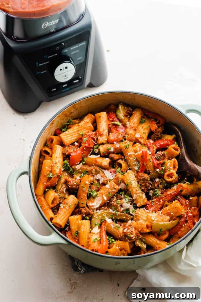 A large pot of the finished rigatoni dish, showing a rich, saucy texture, perfectly integrated pieces of sausage, and tender roasted vegetables, ready to be served.