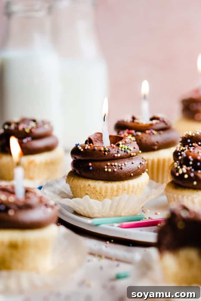 Vibrant yellow birthday cupcakes with decadent malted chocolate frosting, colorful sprinkles, and lit birthday candles, ready for a celebration.