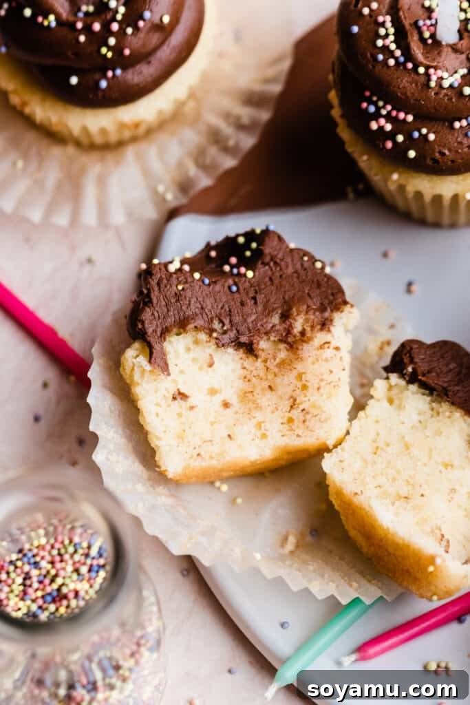 A perfectly baked yellow cupcake cut in half, revealing its moist, fluffy interior and tender crumb.