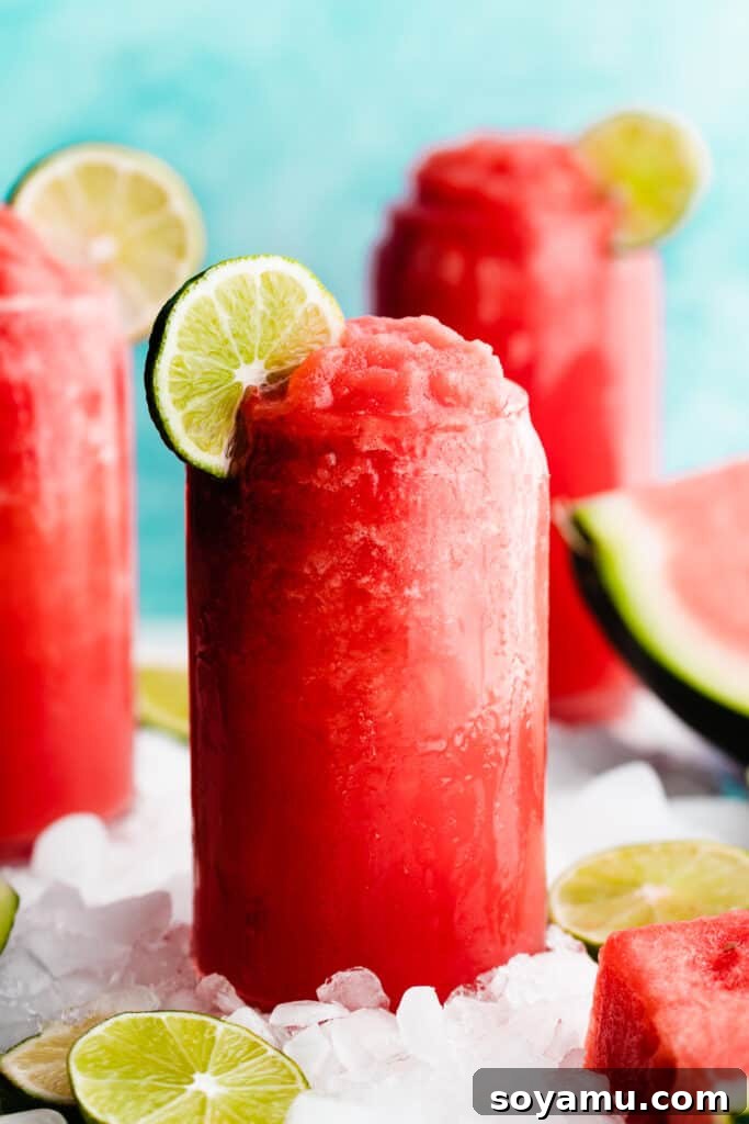Watermelon Wave Frozen Margaritas 3 A close-up of a glass of bright pink frozen watermelon margarita topped with a lime slice.