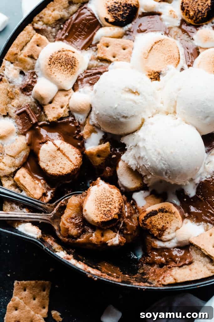 Gooey S'mores Skillet Cookie 8 A close-up of two spoons digging into the gooey s'mores cookie, highlighting the melted chocolate and marshmallow.