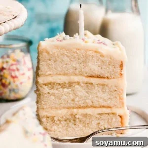 A close-up of a slice of white cake with a birthday candle and sprinkles, with a blue background, invitingly presented.