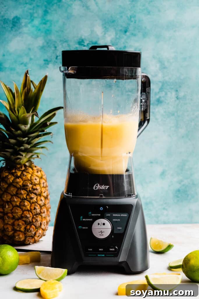 Paradise Frost 5 A blender full of the perfectly blended, bright yellow frozen piña colada drink, ready to be poured.