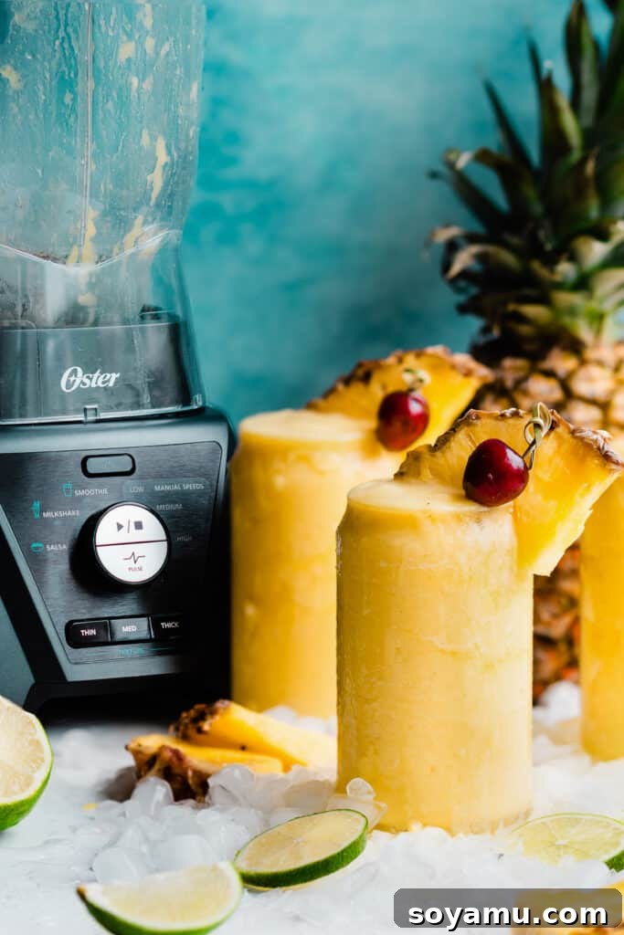 Paradise Frost 8 Glasses of the pineapple drink with a blender in the background, showcasing the tools used to create this delicious beverage.
