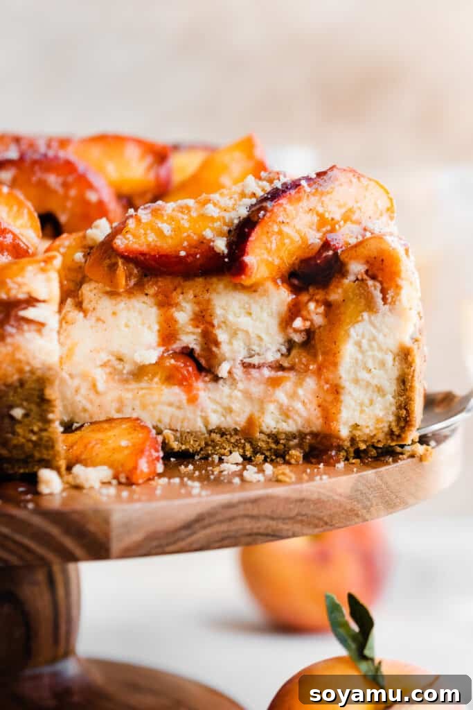 A close-up of a cheesecake slice with peaches in the center and on top, and cinnamon peach juice dripping down, highlighting the rich layers.