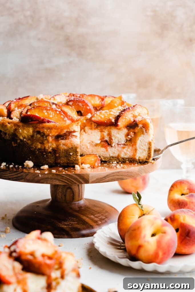 The glorious peach cobbler cheesecake displayed on a cake stand, with several slices already cut, revealing its creamy texture and luscious peach topping.