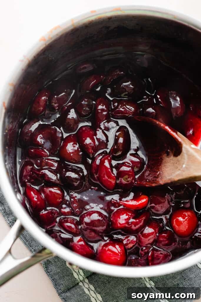 Enchanted White Forest Cake 6 A pot of homemade cherry sauce, simmering and thickening on the stovetop, with vibrant red cherries visible.