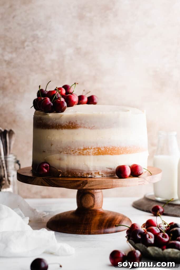 Enchanted White Forest Cake 9 The perfectly frosted and unsliced White Forest Cake, elegantly topped with a generous pile of fresh cherries, ready to be served.