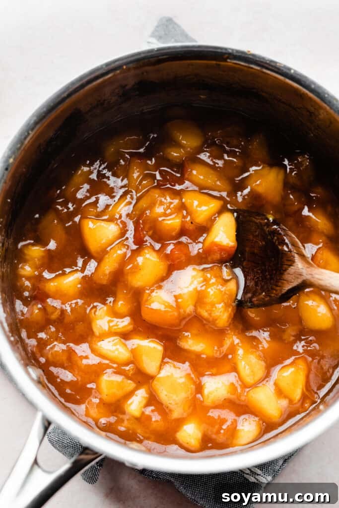 Swirled Homemade Peach Pie Milkshake 4 A saucepan on the stovetop filled with a vibrant peach sauce, bubbling gently as it cooks and thickens, releasing a sweet aroma.