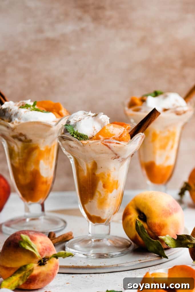 Swirled Homemade Peach Pie Milkshake 9 Three perfectly presented peach milkshakes in traditional old-fashioned glasses, beautifully topped with generous swirls of fresh whipped cream and elegant cinnamon sticks for an inviting garnish.