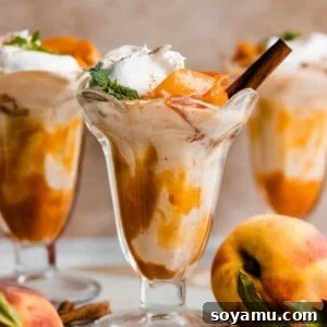Three peach shakes in old fashioned glasses with peach sauce swirled in and peaches and whipped cream on top.