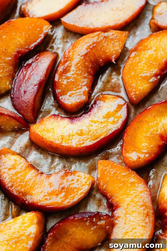 Caramelized Cinnamon Peaches 2 A close-up of beautifully caramelized and juicy roasted peach slices on a parchment paper lined baking sheet, ready to be served.