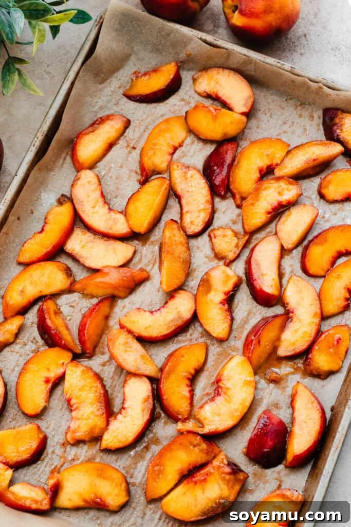 Caramelized Cinnamon Peaches 5 A sheet pan lined with parchment paper, holding cinnamon sugar tossed peach slices, resting before baking.