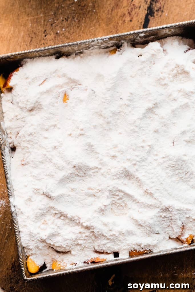 Easy Peachy Cobbler Bake 5 Cake mix poured over the peaches in the baking dish.