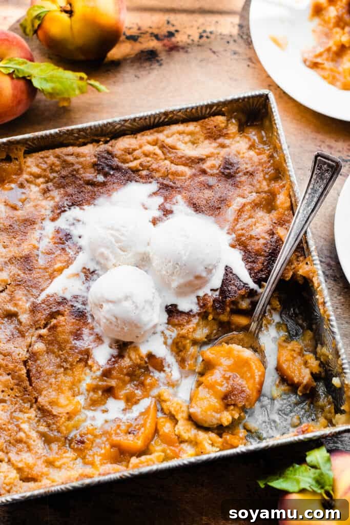 Easy Peachy Cobbler Bake 8 The pan of cake mix peach cobbler with ice cream melting on top.