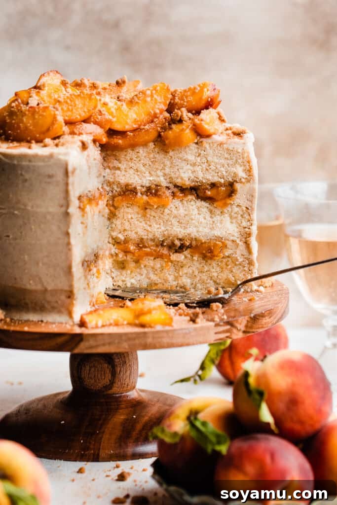 Golden Peach Cobbler Cake with Nutty Brown Butter Frosting 2 A three-layer peach cobbler cake, beautifully assembled with visible layers of creamy brown butter frosting, sweet peach filling, and cinnamon streusel. Fresh peach slices adorn the top.