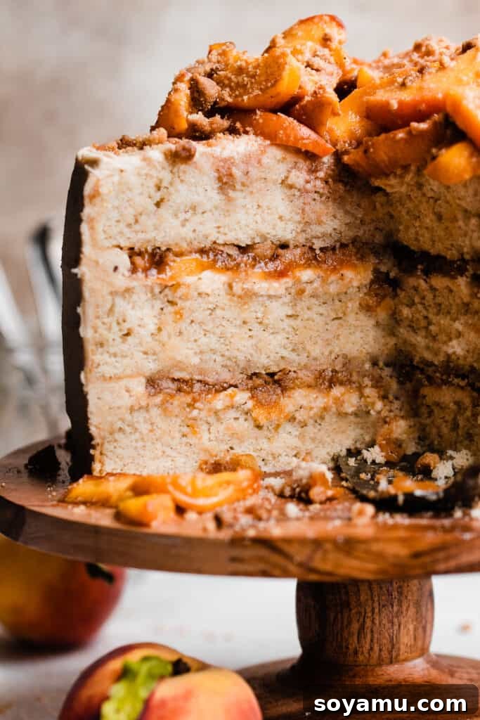 Golden Peach Cobbler Cake with Nutty Brown Butter Frosting 11 A stunning cross-section of the sliced peach cobbler cake, revealing perfect layers of cake, brown butter frosting, peach filling, and streusel.